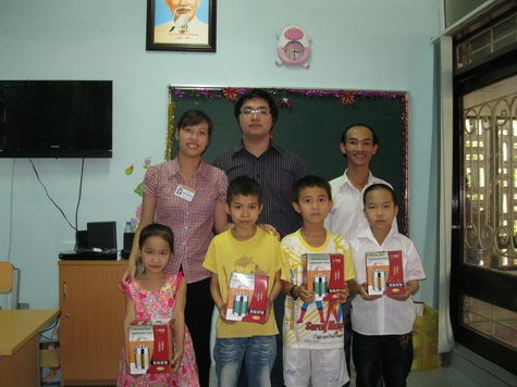 Ông Hoàng Minh Đức (giữa) thay mặt báo Giáo dục Việt Nam trao tặng các em học sinh Lớp học Hy vọng những chiếc cặp lồng xinh xắn từ Thẩm mỹ viện Khang Lệ