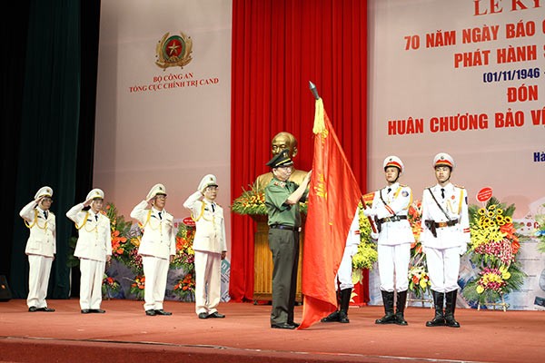 Thừa ủy quyền của Chủ tịch nước, Bộ trưởng Tô Lâm gắn Huân chương Bảo vệ Tổ quốc hạng nhất lên Cờ truyền thống của Báo Công an Nhân dân.